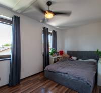 Bedroom with a bed, dark curtains, and wooden floor in a family house.