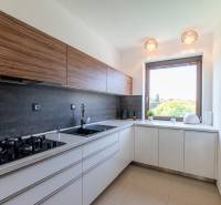 A kitchen in a family house with a gas stove, wooden cabinets, and a large window.