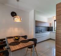 Dining room in a family house with a wooden table, modern lighting fixtures, and a kitchen.