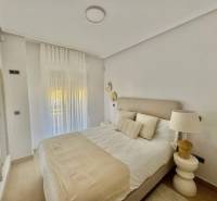 A bedroom in a holiday apartment with a comfortable bed, a mirror, and curtains.