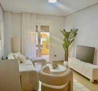 Living room with a sofa, television, and a plant in a holiday apartment.
