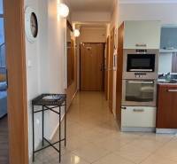 Hallway in a 3-room apartment with a kitchen and built-in appliances, light tiles.