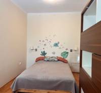 Bedroom in a 3-room apartment with a bed, wall decoration, and storage space.