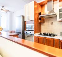 A kitchen in a 3-room apartment with wooden cabinets and a stove, illuminated by natural light.