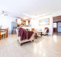 Living room in a 3-room apartment with wooden flooring, a sofa set, and a dining area.