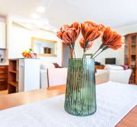 A vase with flowers on the table in a 3-room apartment with a kitchen in the background.