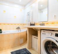 A bathroom with a bathtub, sink, and washing machine in a 3-room apartment.