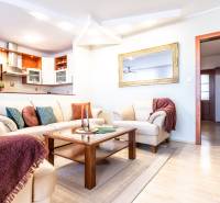 Living room in a 3-room apartment with a sofa, table, and kitchen in the background.