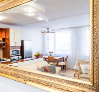 The kitchen and living room of a 3-room apartment captured in a mirror with a gold frame.