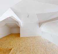 Attic space in a family house with wooden flooring and white walls.