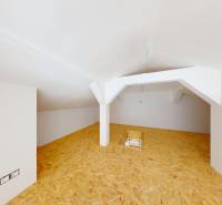 Attic room with wooden floor and white walls in a family house.
