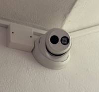 A security camera on the ceiling in a 3-room apartment, a recording device next to it.