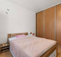 A bedroom with a bed, a nightstand, and a large built-in wardrobe in a 3-room apartment.