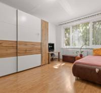 A bedroom with a built-in wardrobe, a sofa, and a window in a three-room apartment.