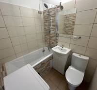 Bathroom in a studio apartment with a bathtub, sink, washing machine, and toilet.