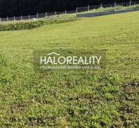 A green grassy plot in Horná Ves suitable for living, fenced, with a forest in the background.