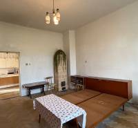 Living room in a one-room apartment with older furniture and entrance to the kitchen.