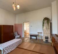 Living room in a one-room apartment with a stove, carpets, and older furniture.