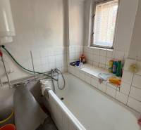 Bathroom with a bathtub and a boiler in a studio apartment, practical storage space on the window.