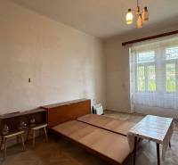 A simple room in a one-bedroom apartment with wooden furniture and a large window.