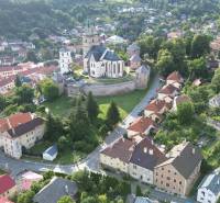 The town of Kremnica with a church and historical buildings surrounded by greenery.