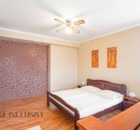 A bedroom with a wooden bed, a fan, and decorative paintings in hotels and guesthouses.