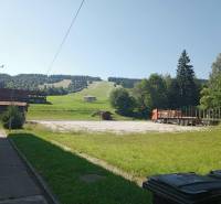 Landscape in Makov with a truck, grassy slope, and trees on the horizon.