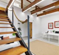 Interior of an office with wooden stairs, a white table and chairs, decorative elements.