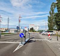Parking lot with a ramp, electrical wiring, buildings, and greenery on Vajnorská Street in Bratislava.