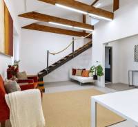 Interior of an office with wooden beams, stairs, comfortable chairs, and decorations.