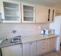 A kitchen unit with a microwave in a 2-room apartment, wooden cabinets with glass doors.