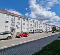 1st May Street in Malacky with parking in front of three-story buildings, visible cars and sidewalk.