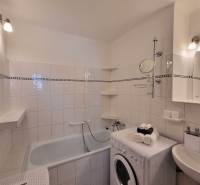 Bathroom with a bathtub, washing machine, and sink in a 2-room apartment.