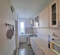 A kitchen in a 2-room apartment with wooden cabinets and appliances.