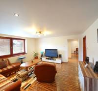 Living room of a family house with a sofa, television, and wooden floor.