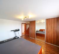 A bedroom in a family house with a bed, a mirrored wardrobe, and a treadmill.