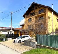 A family house in Vyšná Myšľa with a parked car and a green fence.