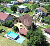 A family house in Vyšná Myšľa with a swimming pool surrounded by greenery and other houses.