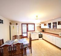 A spacious kitchen with a wooden dining table and kitchen unit in a family house.