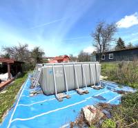 A family house in Vyšná Myšľa with an above-ground pool in a garden surrounded by greenery.