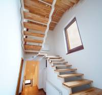 A wooden staircase in a family house with a bright interior and a large window.