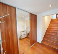 Interior of a family house with a staircase, built-in wardrobe, and shoe cabinet on the tiles.