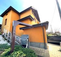 A family house in Vyšná Myšľa with an orange facade and a garden with greenery.