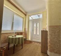 A hallway in a family house with a round table and a green tablecloth.