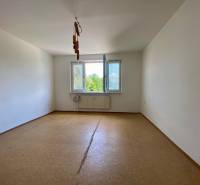 An empty room in a 3-room apartment with a window and a radiator on the wall.