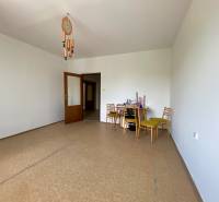 A spacious room with a dining table in a 3-room apartment, wooden chairs and a chandelier.