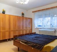 A bedroom in a family house with a bed, a wooden wardrobe, and a window with a radiator.