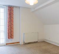 Interior of a family house with a curtain, radiator, and white wall.