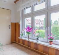 A room in a family house with large windows and flowers on the windowsill.