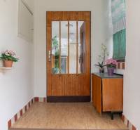 Entrance in a family house with glass doors and flowers on shelves.